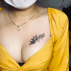 A delicate floral bouquet tattoo on the chest. The black and grey shading gives the flowers a soft, realistic look.
