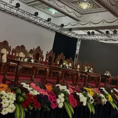 A closer look at the detailed decor for a formal dais. The stage is lined with a dense, colorful floral runner, and the official lectern is accented with a matching floral piece.