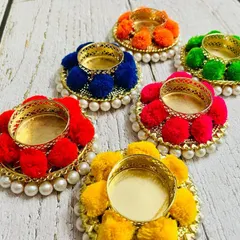A set of my assorted pompom tea light holders. The combination of bright colors, delicate pearls, and a golden holder makes them a beautiful addition to your Diwali or party decor.
