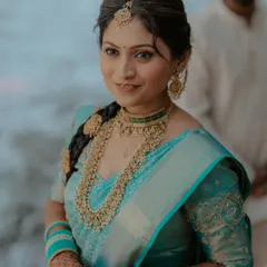 A stunning portrait of a bride in a turquoise blue Kanjeevaram saree. Her look is completed with a traditional long braid, temple jewelry, and glowing makeup.
