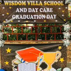 A graduation day backdrop for a school and daycare, complete with a custom banner and star-shaped foil balloons.