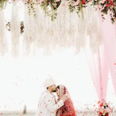 A destination wedding dream realized. Under a canopy of flowers on a serene beach, the groom kisses his bride's forehead, a perfect, timeless moment framed against the vastness of the sea.