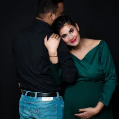 Sometimes the most powerful images are the quiet ones. Here, the mother-to-be rests her head on her partner's shoulder, creating a moment of serene connection. The dark background and rich green dress make the portrait feel intimate and classic.