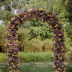 A whimsical floral arch created for an outdoor Mehendi. We used a lush combination of sunflowers, marigolds, and rich purple blooms to craft a vibrant and enchanting gateway for guests.