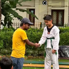A handshake of congratulations during a color belt ceremony. Recognizing progress is an important part of building a student's confidence.