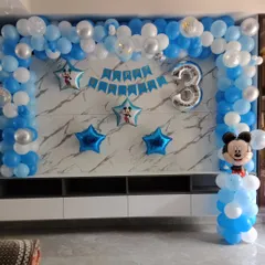 A simple and sweet Mickey Mouse decoration for a 3rd birthday, set up against a home's TV unit. I used a blue and white balloon arch, star-shaped foil balloons, a '3' foil balloon, and a Mickey Mouse balloon character to create a festive corner.