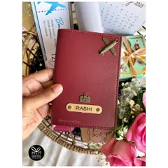 A personalized passport holder with the recipient's name and custom charms. This is a great standalone gift or a perfect addition to a travel-themed hamper.
