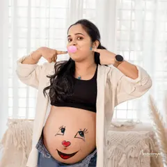 A fun and playful shot! This mom-to-be opted for a cute smiley face painted on her bump, adding a touch of humor and personality to her studio session.