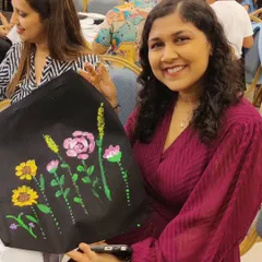 A guest at Canny's baby shower shows off the beautiful floral design she painted on a black tote bag for the mom-to-be.
