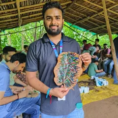 A KPMG employee proudly displays his artwork from our leaf painting session. This creative activity is a great way to connect with nature on an artistic level.