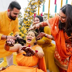 The bride's friends and family lovingly applying Haldi. This image is all about the shared joy and community of a wedding.