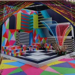 A vibrant and psychedelic carnival-themed brunch, featuring a stage with geometric patterns, bold colors, and string art installations for a fun and high-energy event.