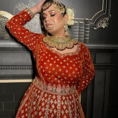 Here is a close-up of a royal bridal outfit I designed. You can see the rich texture of the red-orange velvet and the detailed silver and turquoise embroidery around the neckline. I focus on using luxurious fabrics to create these timeless pieces.