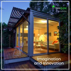 This cozy, light-filled prefab structure serves as a small home or guest house. The combination of a wooden deck, slatted pergola, and full-height glass walls creates a functional and beautiful living space.