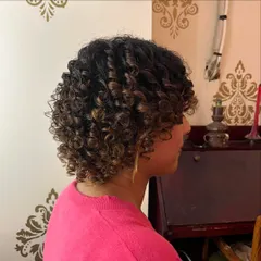 A side view showing the defined curl pattern and volume achieved with this curly bob haircut.