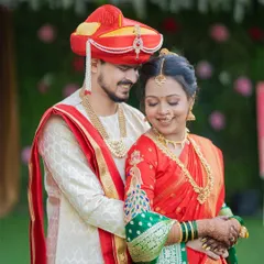 A beautiful portrait of a Maharashtrian couple, with the bride in a classic red and green Paithani saree and the groom in a matching red pheta.