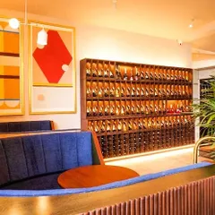 The interior of Haute, a wine bar we designed in Indiranagar, Bengaluru. The space features plush booth seating, a prominent wine display, and bold artwork to create a sophisticated and inviting atmosphere.
