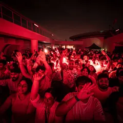 The crowd lost in the music under intense red lighting. We use lighting design to create powerful, immersive moods that amplify the energy of the dance floor.