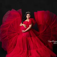This shot captures the full splendor of the red gown against a simple black background, emphasizing its vibrant color and form.