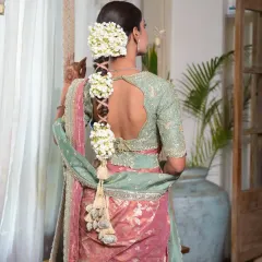 A back view showcasing the full length and detail of a criss-cross patterned gajara braid. The combination of the intricate braid and fresh flowers makes it a standout feature for this bridal campaign look.