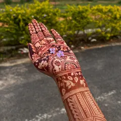 A single hand held up to show the deep, even stain. The small flower adds a touch of delicacy to the powerful color.