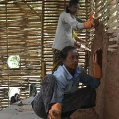 Two of our skilled masons applying daub to a bamboo wattle wall. Through our training, these women master sustainable building practices, gaining confidence and creating positive change in their communities.