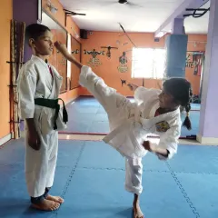 A young student practices a high kick during a karate class. We focus on proper technique and safety.