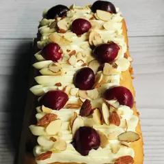This is my Cherry Almond Tea Cake. It’s a moist almond cake with sweet cherry flavors, topped with almond buttercream, fresh cherries, and crunchy sliced almonds.