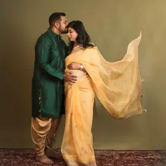 A tender kiss for his wife and their coming baby. This image captures the love and support between partners during a traditional maternity session, set against a classic studio backdrop.