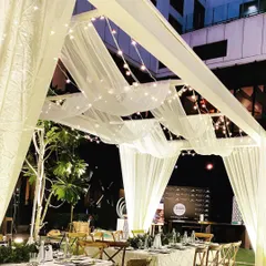 Another view of the beautiful outdoor dinner setup, showing the elegant white canopy structure and the warm, inviting glow of the lighting against the night sky.