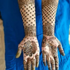 A lovely engagement mehendi in an Indo-Arabic style. It features a large, stylized peacock on one palm and a net pattern on the arms.