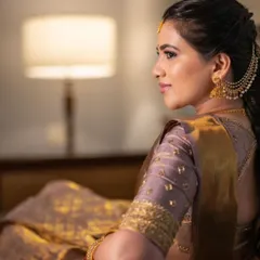 A side profile of a classic South Indian look, featuring a beautiful saree and traditional gold jewelry.