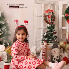 A magical Christmas, beautifully captured. This toddler is all smiles in her festive dress, surrounded by presents, trees, and a snowman.