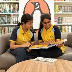 Two students sharing a book after school. Our bookstore is a welcoming space for kids to unwind, do their reading, and discover new titles together.
