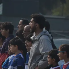 A coach watches intently from the sidelines with parents and players. We are a community of players, coaches, and families all invested in the journey.