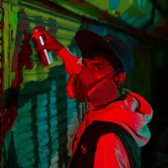 A portrait of me at work, caught in a red light. Safety is key, but the respirator has also become a part of the iconic look of a graffiti artist.