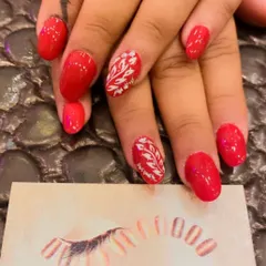 A simple and elegant set of bright red almond nails. The ring fingers are accented with a delicate, hand-painted white leaf pattern.