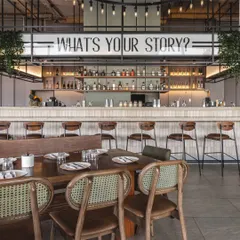 For Prequel, the bar is the heart of the space. We placed the brand's tagline, 'What's your story?', front and center to spark conversation, creating a focal point that is both a service area and a statement piece reflecting the restaurant's social, narrative driven identity.