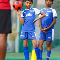 There is no learning without fun. A young player holds the ball with a confident pose, ready for the next drill.