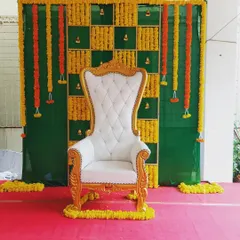 For this Seemantha function, I focused on classic elements. The decor includes a white and gold ornate chair set against a backdrop of green fabric and fresh marigold flower garlands.