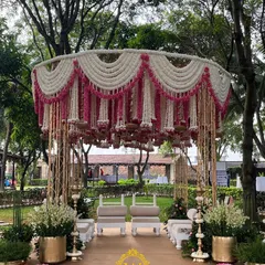 An absolutely breathtaking traditional mandap design. The structure is adorned with hanging garlands of pink and white rajnigandha, with brass urli bowls creating a stunning floral chandelier effect.