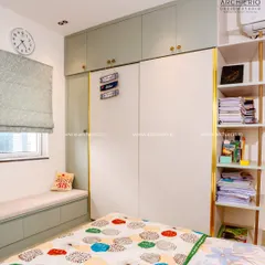 A practical and stylish teen's room with a two-tone wardrobe, a window seat with storage, and open shelving for books and decor.