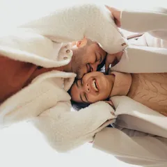 A creative, joyful shot taken from below, capturing the couple's infectious laughter as they lie together in a happy embrace.