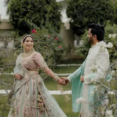 A candid moment of the couple walking hand-in-hand through a lush garden, their smiles reflecting their happiness.