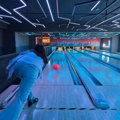 Feel the energy of our neon-lit bowling alley. This is a perfect wide-angle view of the action, showing a player about to release the ball down the glowing lane, ready for that satisfying strike.