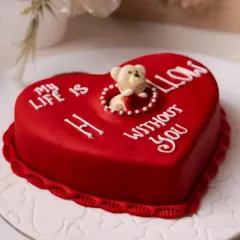 A playful and romantic Valentine's cake with the message "My life is hollow without you," featuring a cute teddy bear peeking out from the center.