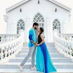 A romantic pose on a grand white staircase. The flowing ombre blue gown adds a splash of color and elegance, making this pre-wedding photo truly memorable.