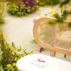 An intimate guide to a lifetime of togetherness. A personalized wedding handbook rests on a cane bench, a small, thoughtful detail for guests to enjoy during the ceremony.