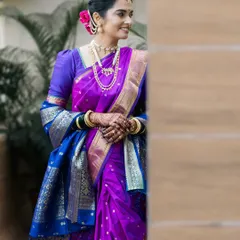 A stunning Maharashtrian bride in a vibrant purple and blue Nauwari saree, captured in a quiet, elegant portrait.