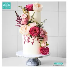 This elegant two-tiered cake showcases a beautiful cascade of fresh pink and cream roses. A touch of hand-painted floral detail on the bottom tier adds a unique, artistic element perfect for a sophisticated wedding or anniversary celebration.